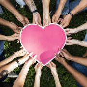 Group of people holding a pink heart icon